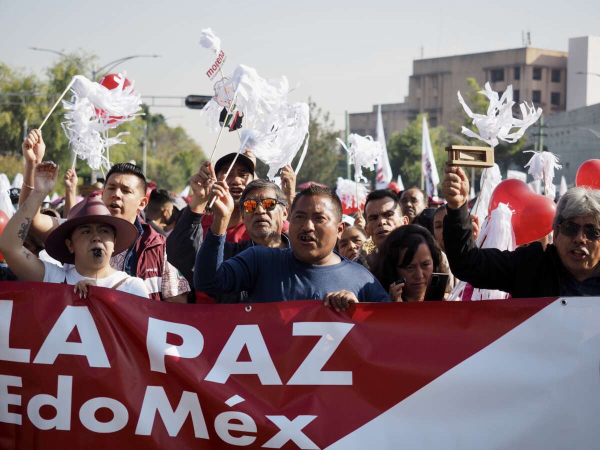 Two supporters of Mexican President Andrés Manuel López Obrador, holding signs rejecting the notion they were coerced into attending a pro-government demonstration, wait along Mexico City’s Paseo de la Reforma for the president to walk by during a rally and march in the capital, November 27, 2022.