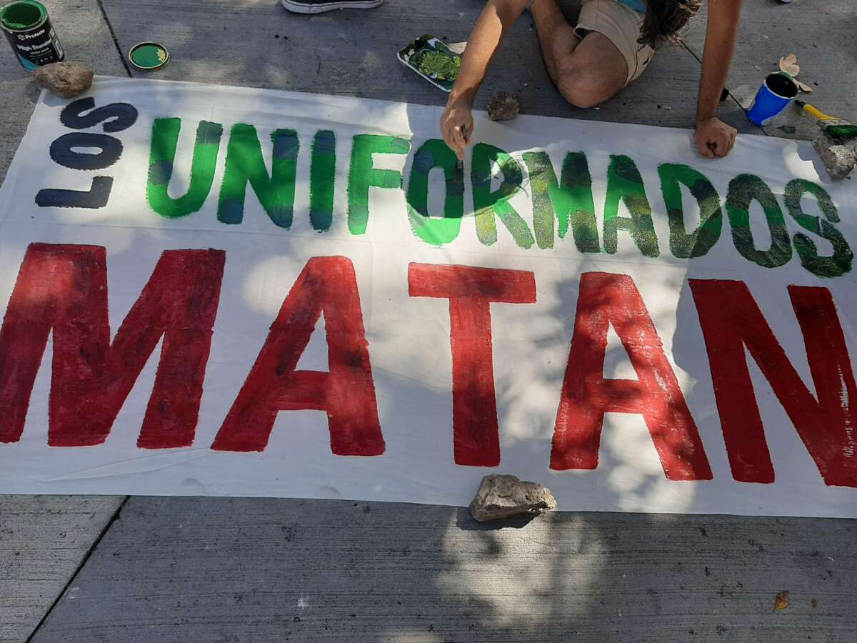 Anti-militarist activists paint a banner that says "those in uniform kill" on December 10, 2022, in Plaza La Merced, Tegucigalpa, Honduras.