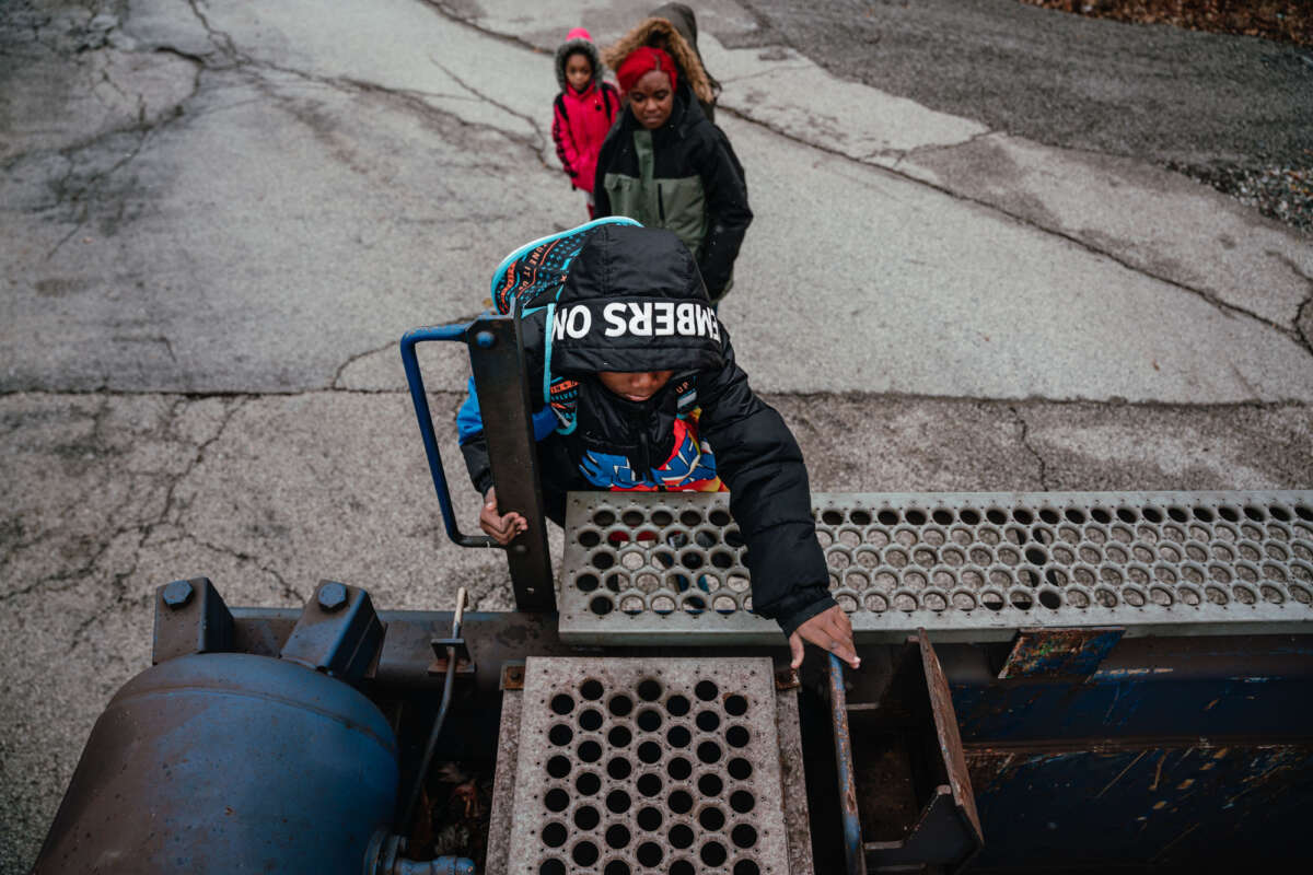 Jeremiah Johnson and his mother, Lamira Samson, climb over a parked freight train on their way to school.