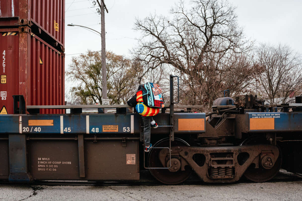 Jeremiah Johnson and his mother, Lamira Samson, climb over a parked freight train on their way to school.