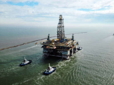 In this aerial image from a drone, tug boats tow the semi-submersible drilling platform Noble Danny Adkins through the Port Aransas Channel into the Gulf of Mexico on December 12, 2020, in Port Aransas, Texas.