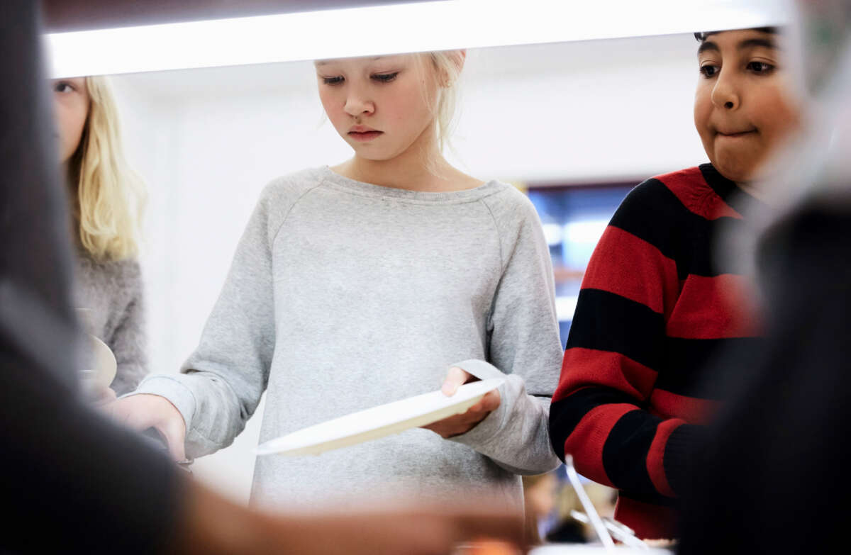 Kids hold plates in line for school lunch