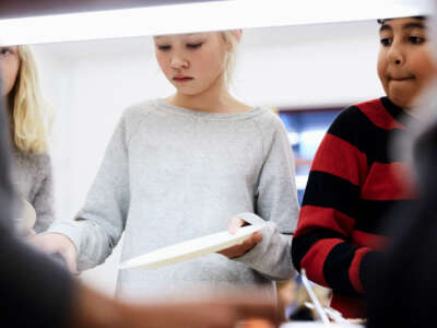 Kids hold plates in line for school lunch