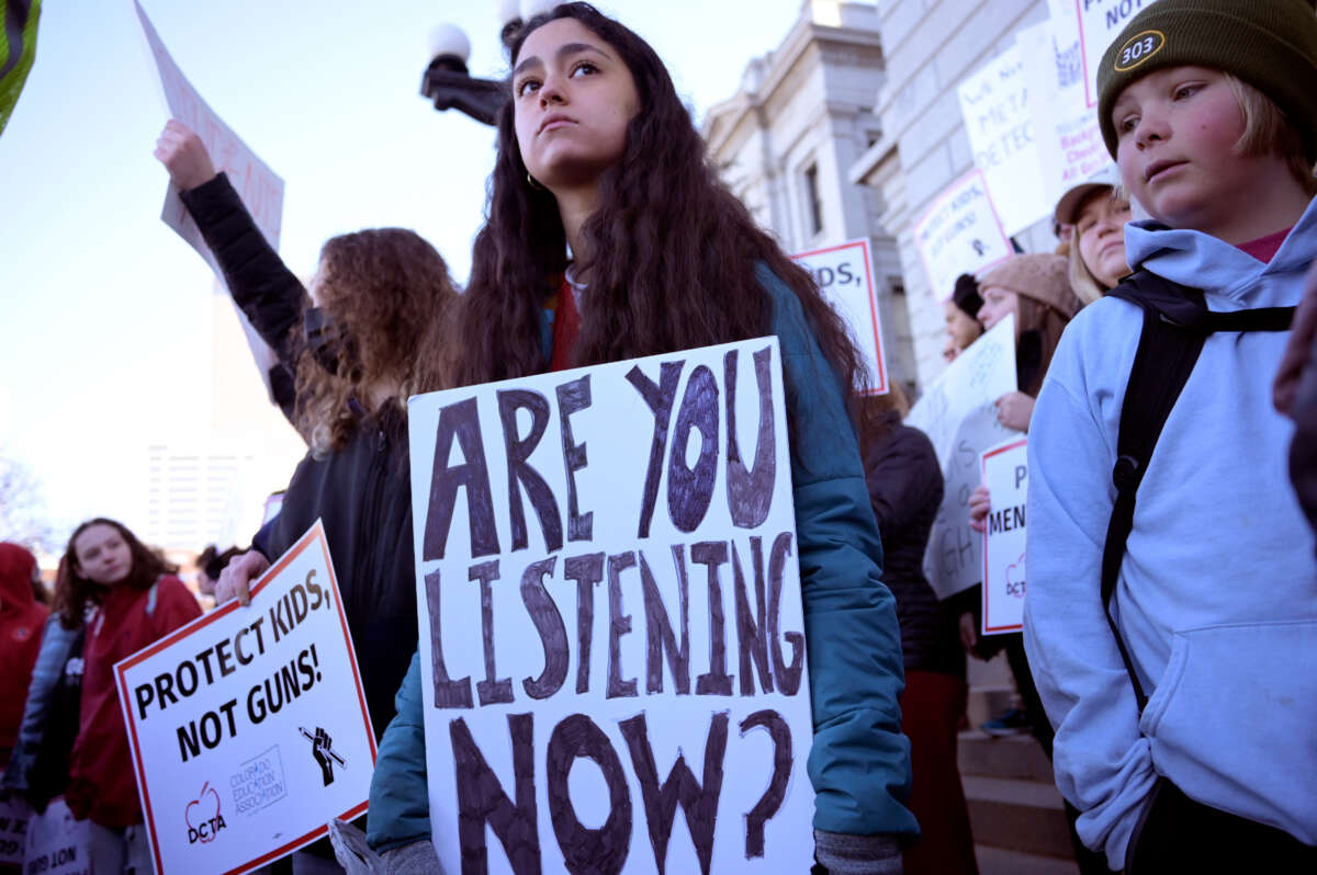 Students participate in the Show Up to End Gun Violence rally at Colorado State Capitol in Denver, Colorado on March 24, 2023. A youth in the middle holds a sign reading 'are you listening now?' while another sign reads 'Protect Kids, Not Guns!'