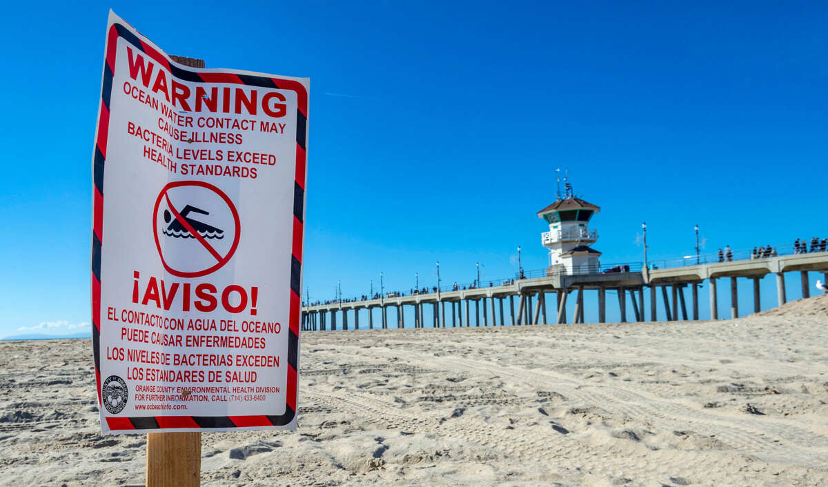 A sign warning people not to swim in toxic water is posted on a beach