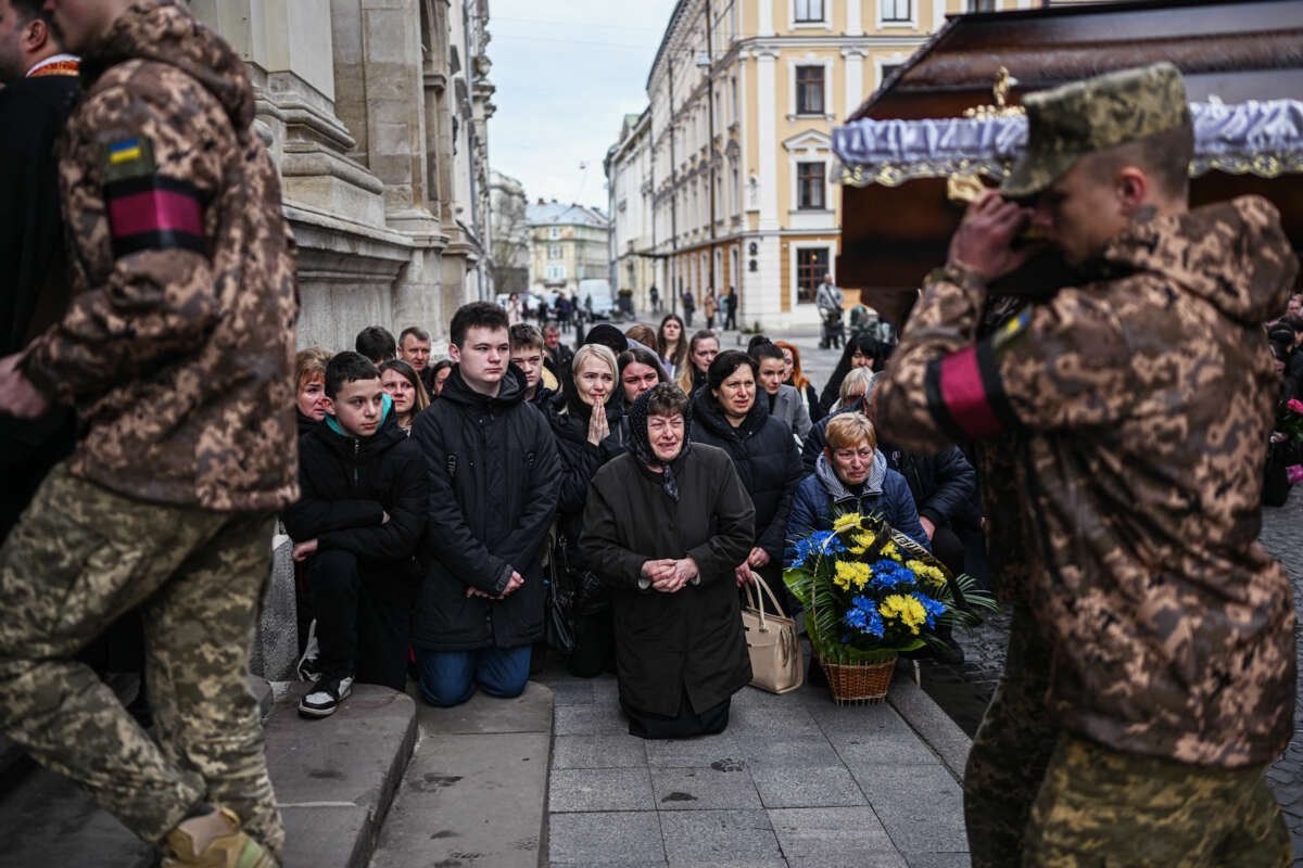 People grieve in public as coffins are marched past them by univormed army personnel