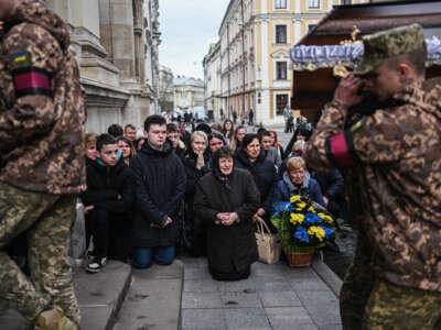 People grieve in public as coffins are marched past them by univormed army personnel