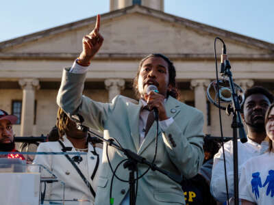 Tennessee State Rep. Justin Jones speaks into a microphone while pointing at the sky