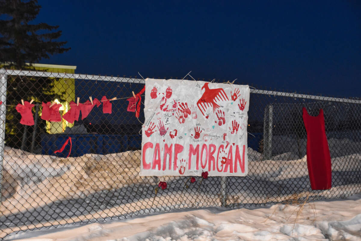 Small red dresses with the names of Murdered and Missing Indigenous Women, Girls and Two-Spirit people hang near a sign for Camp Morgan on the fence surrounding the Brady Road landfill outside Winnipeg, Manitoba, on March 3, 2023.