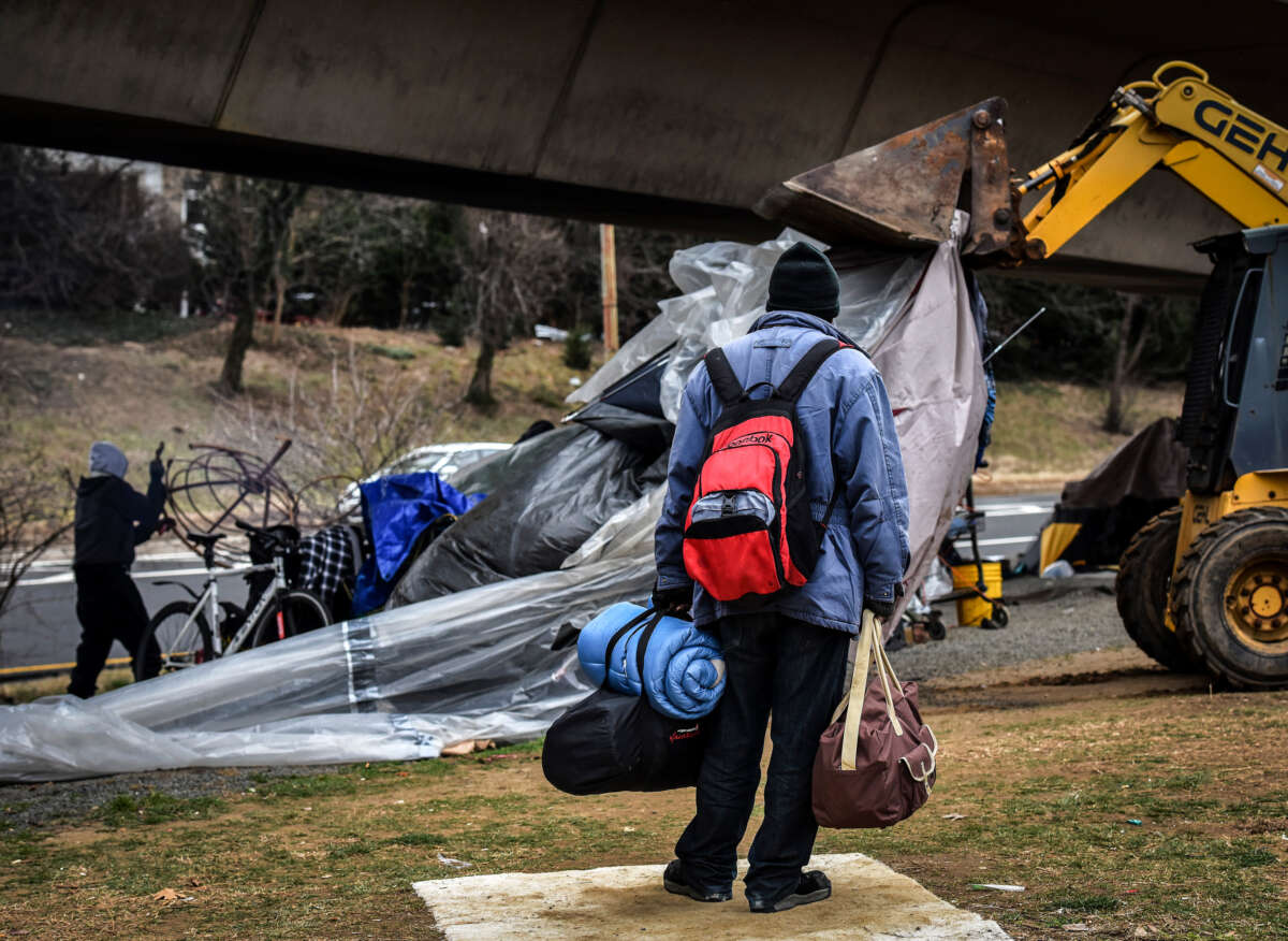 A homeless man carries his possessions as he watches authorities clear out a homeless tent encampment beneath the Whitehurst freeway, on February, 14, 2017, in Washington, D.C.