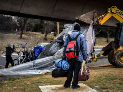 A homeless man carries his possessions as he watches authorities clear out a homeless tent encampment beneath the Whitehurst freeway, on February, 14, 2017, in Washington, D.C.