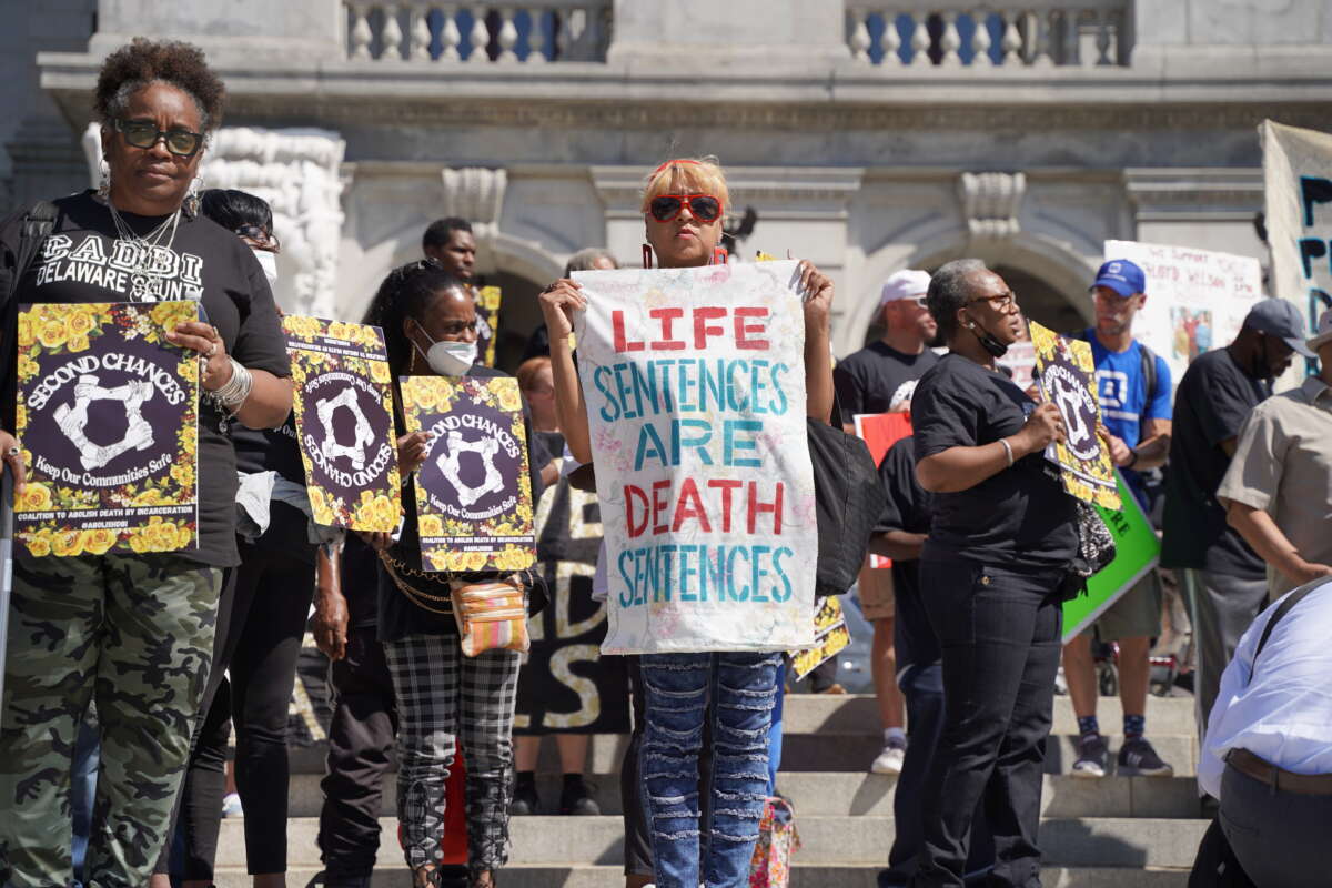 A woman holds a sign that reads "Life Sentences Are Death Sentences" on the steps of the state capitol in Harrisburg, Pennsylvania, on September 20, 2022, at the Second Chances Make Our Communities Safer rally organized by the Coalition to Abolish Death by Incarceration.