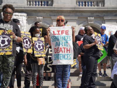 A woman holds a sign that reads "Life Sentences Are Death Sentences" on the steps of the state capitol in Harrisburg, Pennsylvania, on September 20, 2022, at the Second Chances Make Our Communities Safer rally organized by the Coalition to Abolish Death by Incarceration.