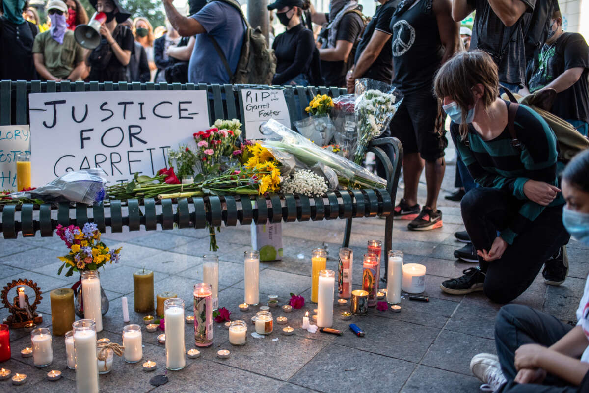 An attendee kneels at a memorial at a vigil for Garrett Foster, who was killed at a Black Lives Matter protest, on July 26, 2020 in downtown Austin, Texas.