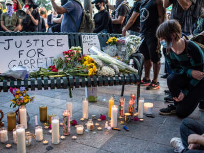 An attendee kneels at a memorial at a vigil for Garrett Foster, who was killed at a Black Lives Matter protest, on July 26, 2020 in downtown Austin, Texas.