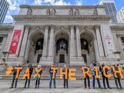 Protesters hold signs spelling out "Tax the Rich" outside the New York Public Library