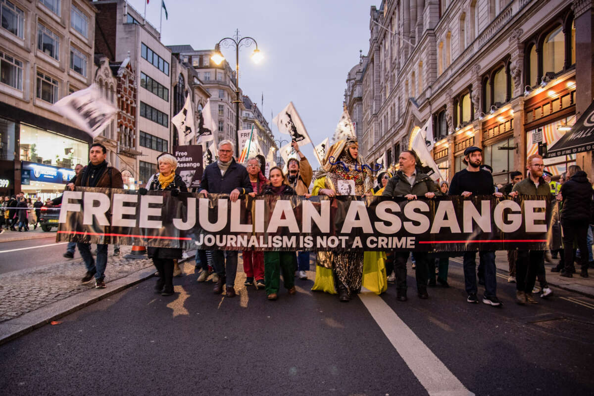 Julian Assange supporters dress in costumes and hold a large banner during a procession in London, UK, on February 11, 2023.