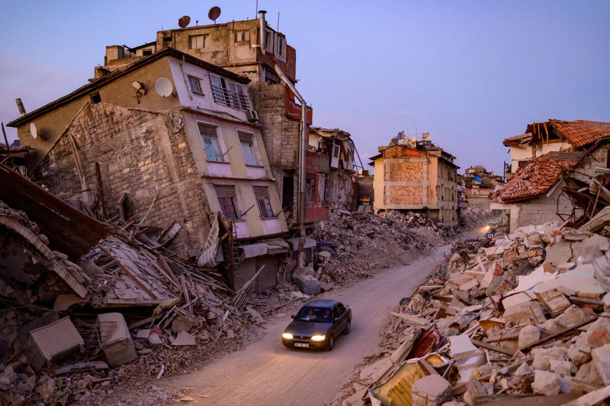 A car drives past collapsed buildings in Antakya, Turkey, on February 20, 2023.