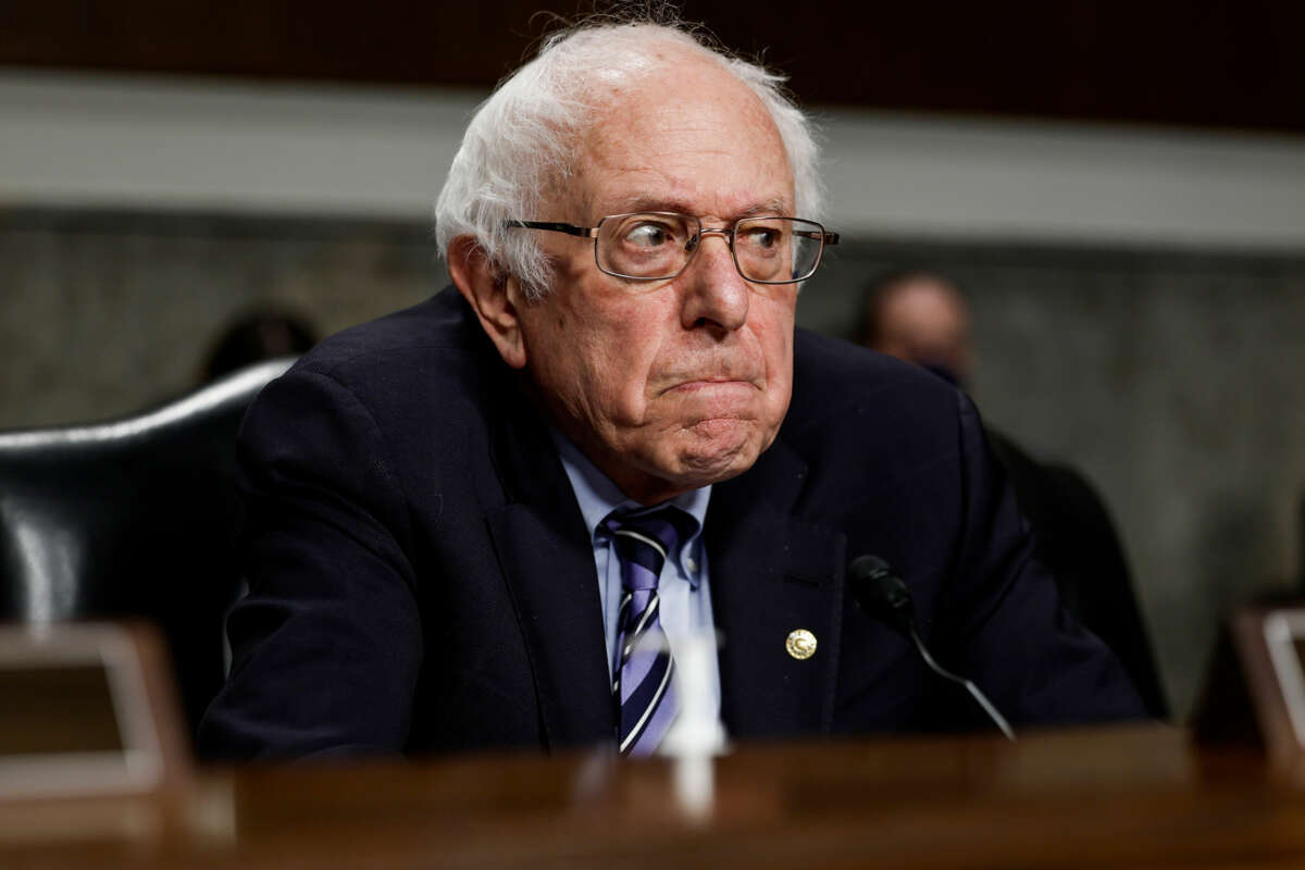 Bernie Sanders frowns and glowers in the direction of someone out of frame