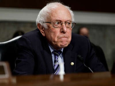 Bernie Sanders frowns and glowers in the direction of someone out of frame