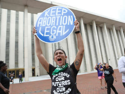 A protester holds a sign reading "KEEP ABORTION LEGAL" during an outdoor protest