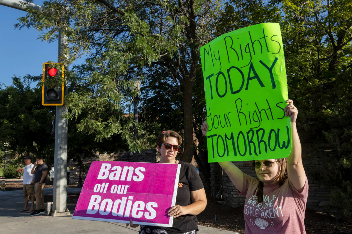 two protesters display signs in support of continued abortion acces, one reading "BANS OFF OUR BODIES" and the other reading "MY RIGHTS TODAY; YOUR RIGHTS TOMORROW"