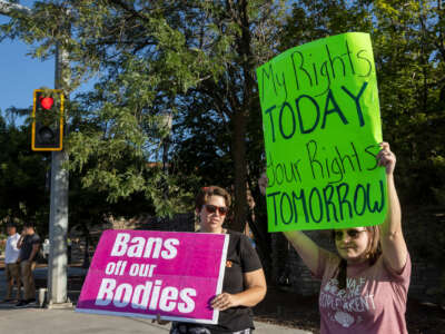 two protesters display signs in support of continued abortion acces, one reading "BANS OFF OUR BODIES" and the other reading "MY RIGHTS TODAY; YOUR RIGHTS TOMORROW"