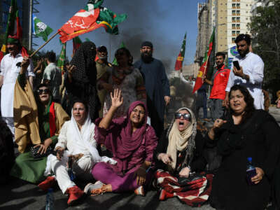 Protesters block the street and wave Pakistani flags during an outdoor demonstration