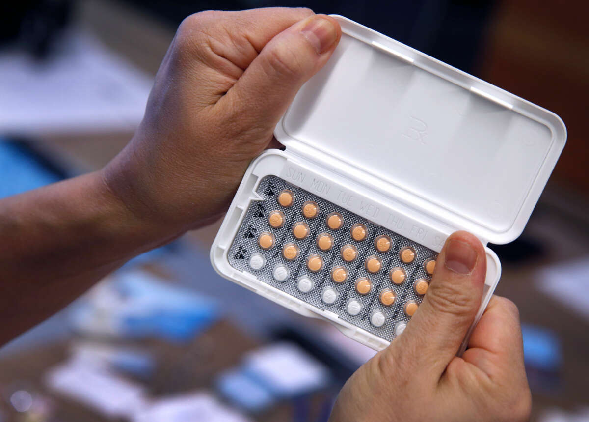 A person holds a compact of birth control pills in both hands