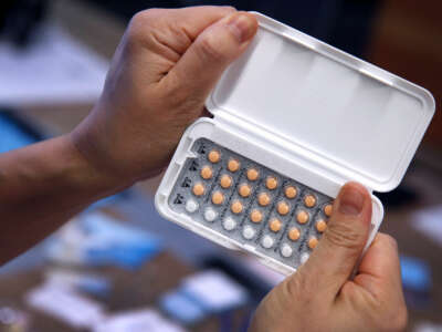 A person holds a compact of birth control pills in both hands