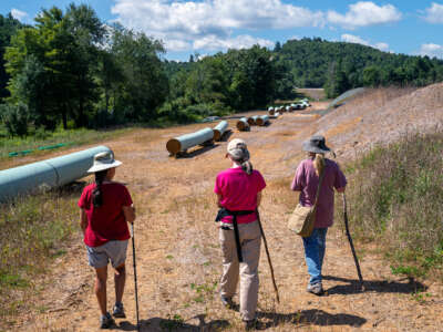 Three hikers point to the laid-out sections of pipe designated for the mountain valley pipeline project