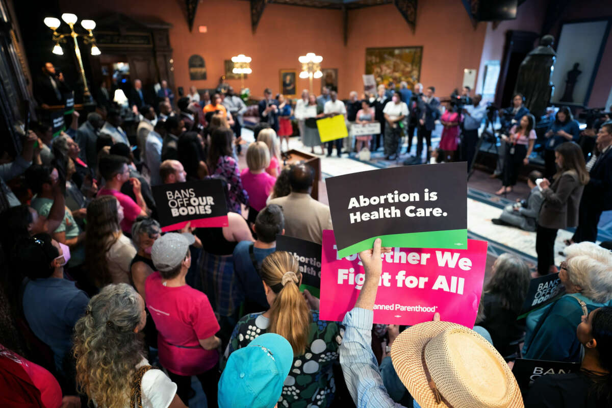 People hold signs reading "BANS OFF OUR BODIES" and "ABORTION IS HEALTHCARE" during a town hall meeting