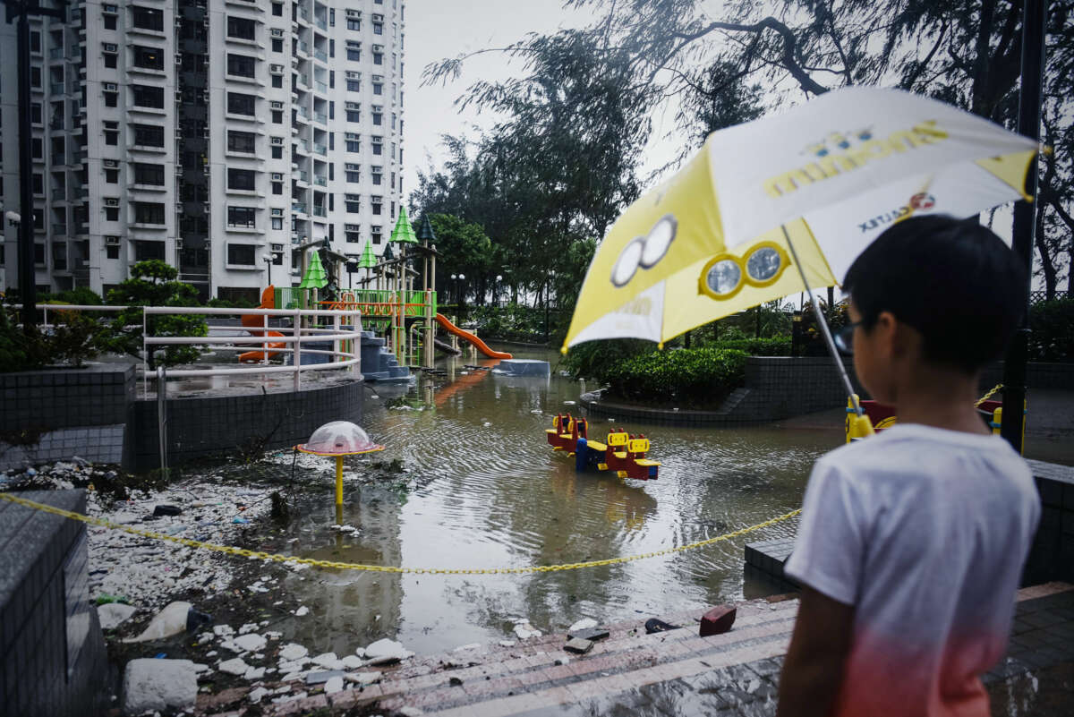 A child looks out onto an inaccessibly flooded playground