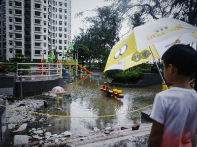 A child looks out onto an inaccessibly flooded playground