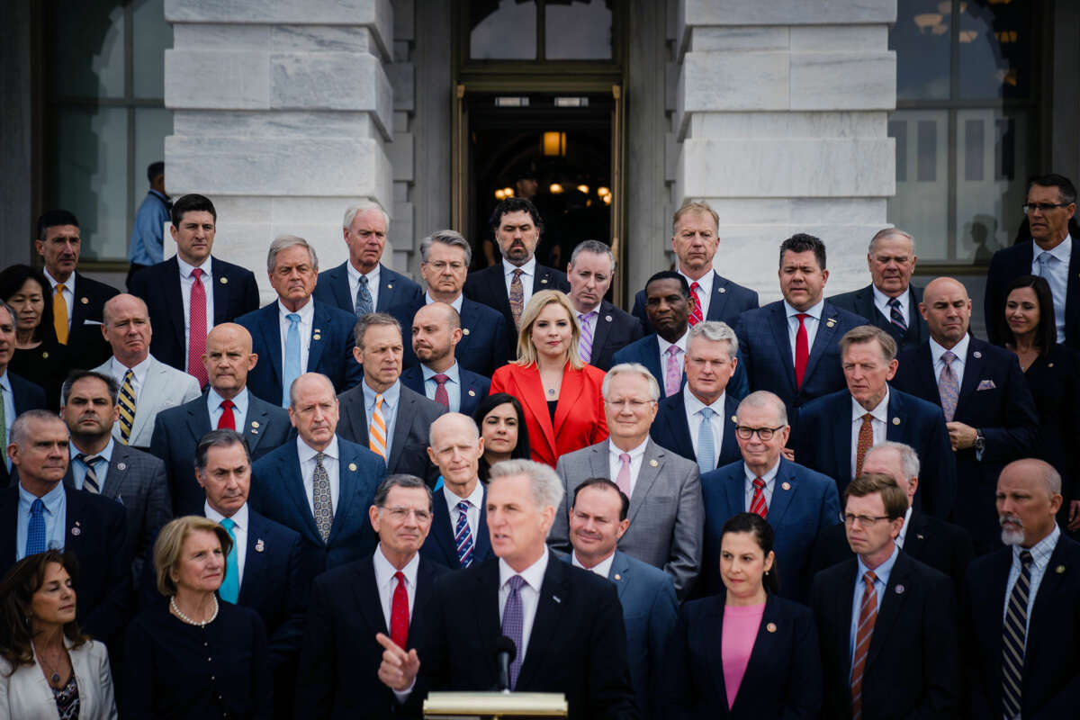 House and Senate republicans stand behind Kevin Mccarthy as he speaks into a microphone