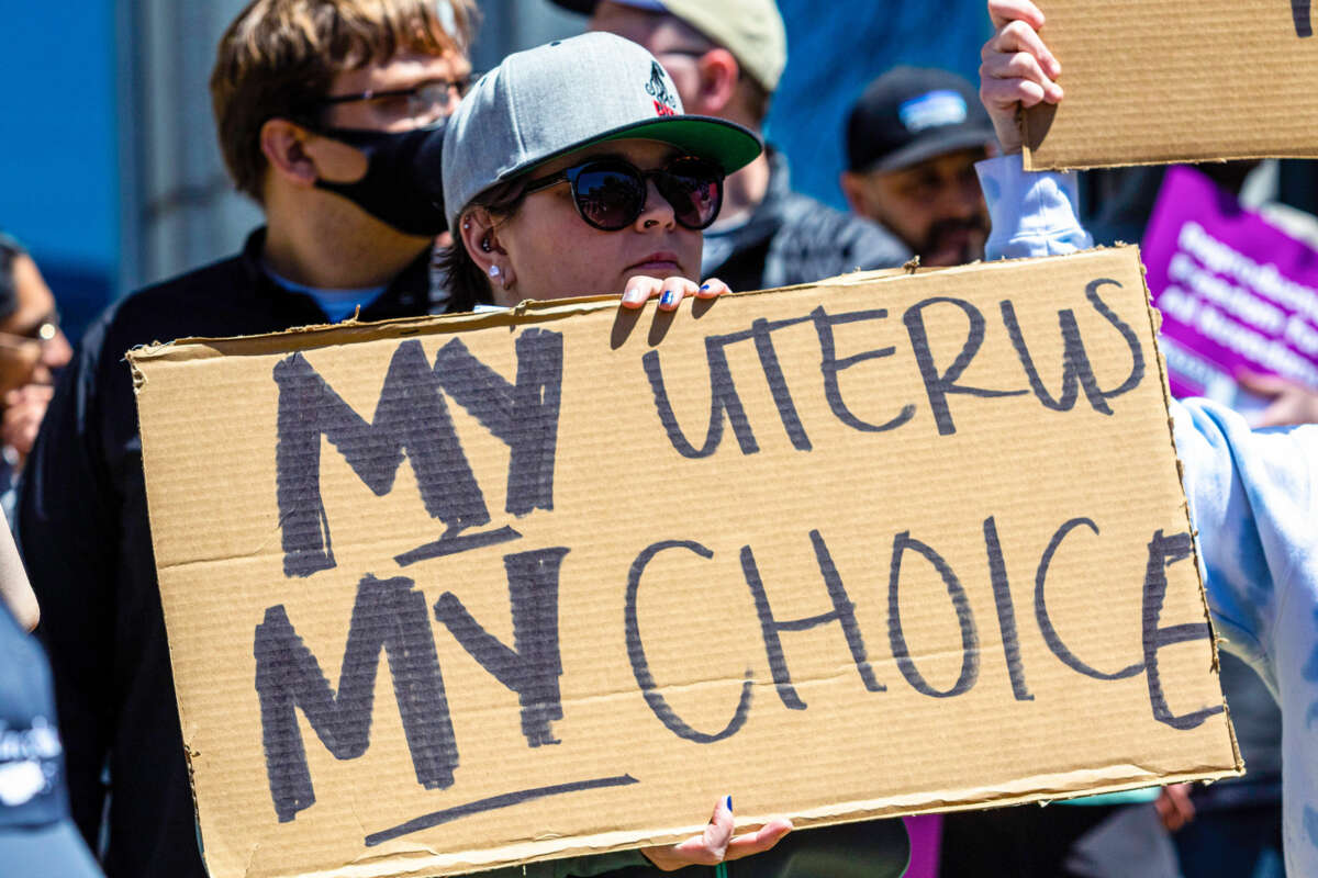A person holds a sign reading "MY UTERUS MY CHOICE" during an outdoor protest