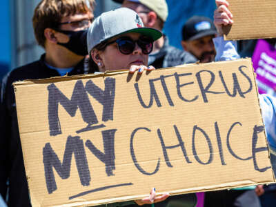 A person holds a sign reading "MY UTERUS MY CHOICE" during an outdoor protest