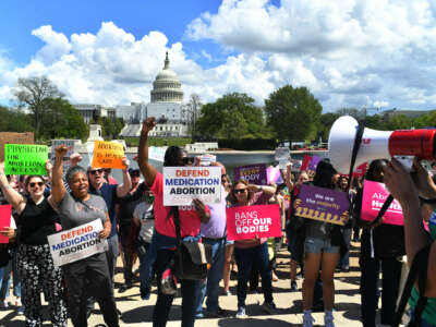 People display signs reading "BANS OFF OUR BODIES" and "DEFEND MEDICATION ABORTION" during an outdoor protest