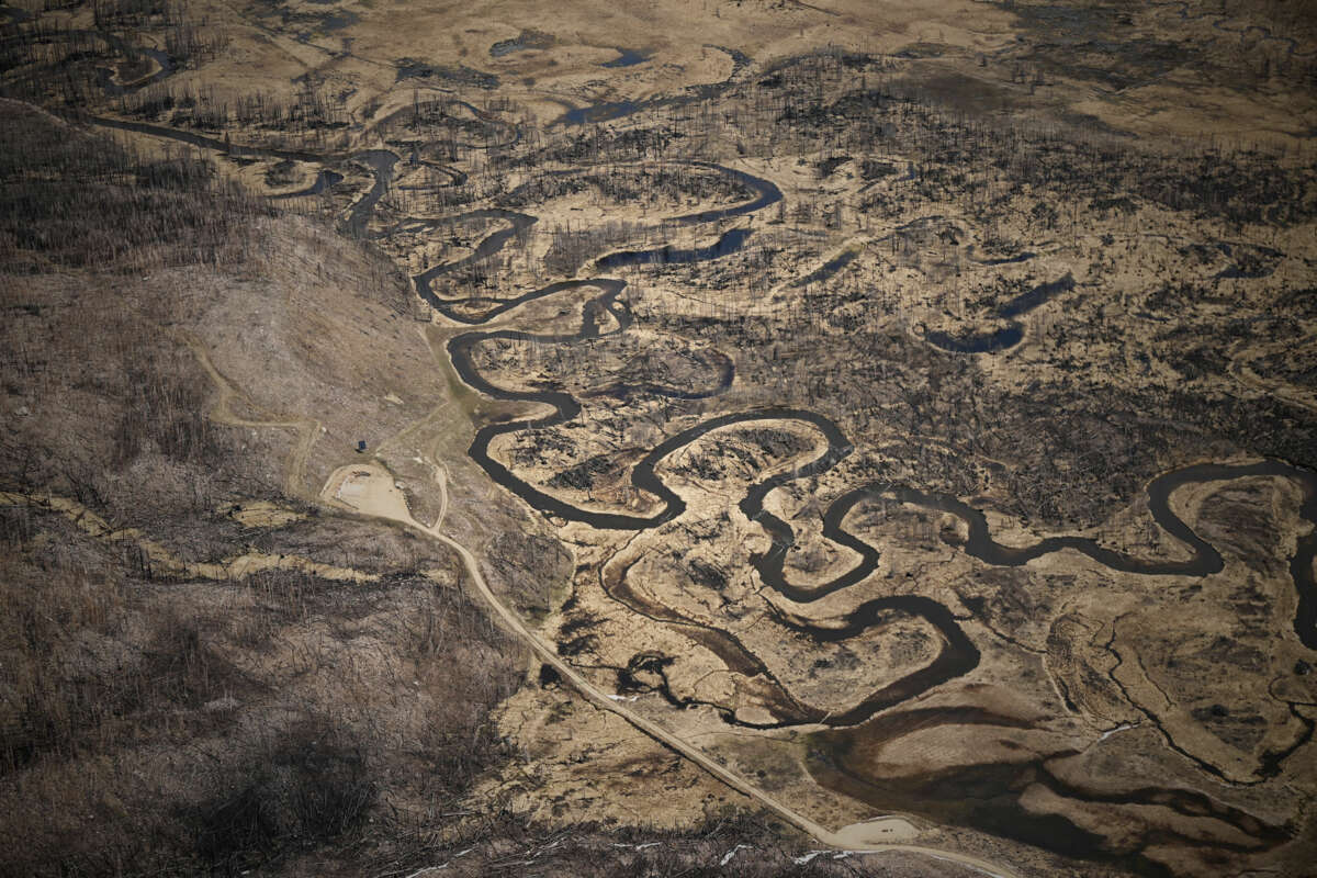 The dwindling Colorado river runs through the brown ground of a burnt forest