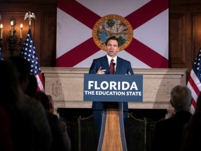 Ron Desantis speaks behind a podium with a sign reading "FLORIDA: THE EDUCATION STATE"