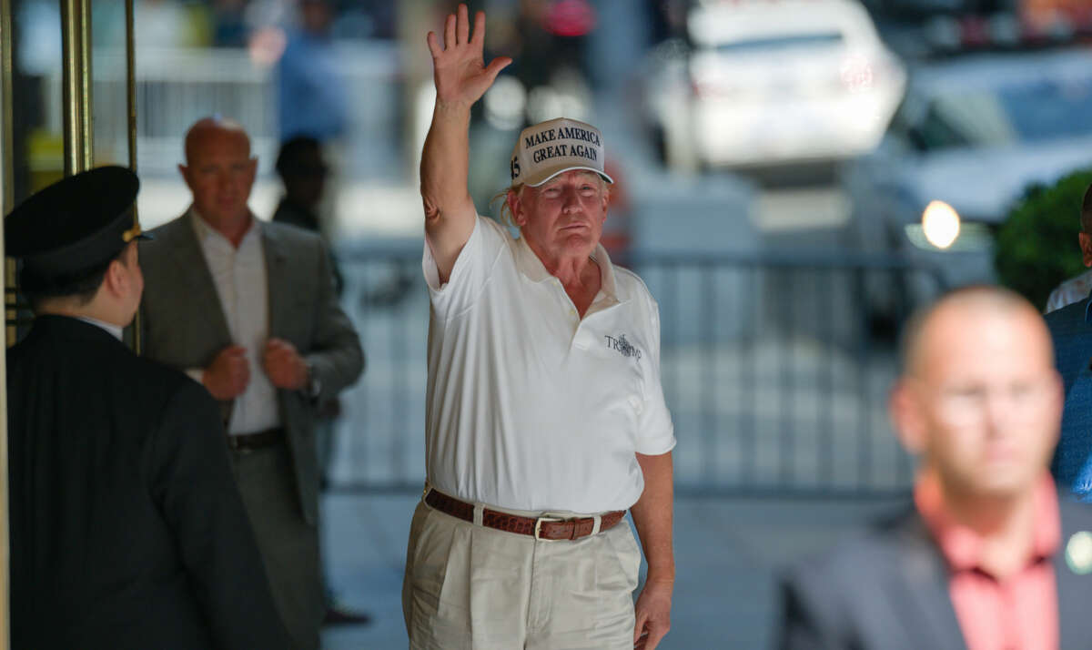 An untanned Donald Trump gestures to photographers