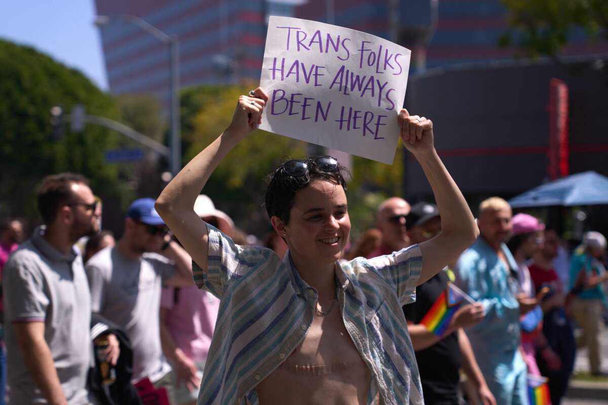 A transgender person holds a sign reading "Trans Folks Have Always Been Here" as LGBTQ+ activists march during the Los Angeles LGBT Center's "Drag March LA: The March on Santa Monica Boulevard," in West Hollywood, California, on April 9, 2023.