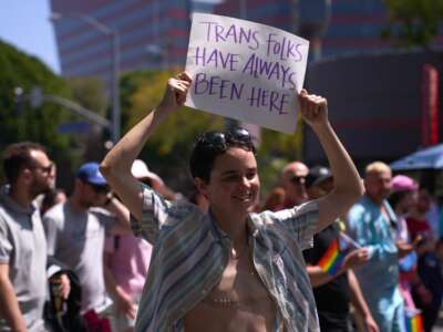 A transgender person holds a sign reading "Trans Folks Have Always Been Here" as LGBTQ+ activists march during the Los Angeles LGBT Center's "Drag March LA: The March on Santa Monica Boulevard," in West Hollywood, California, on April 9, 2023.