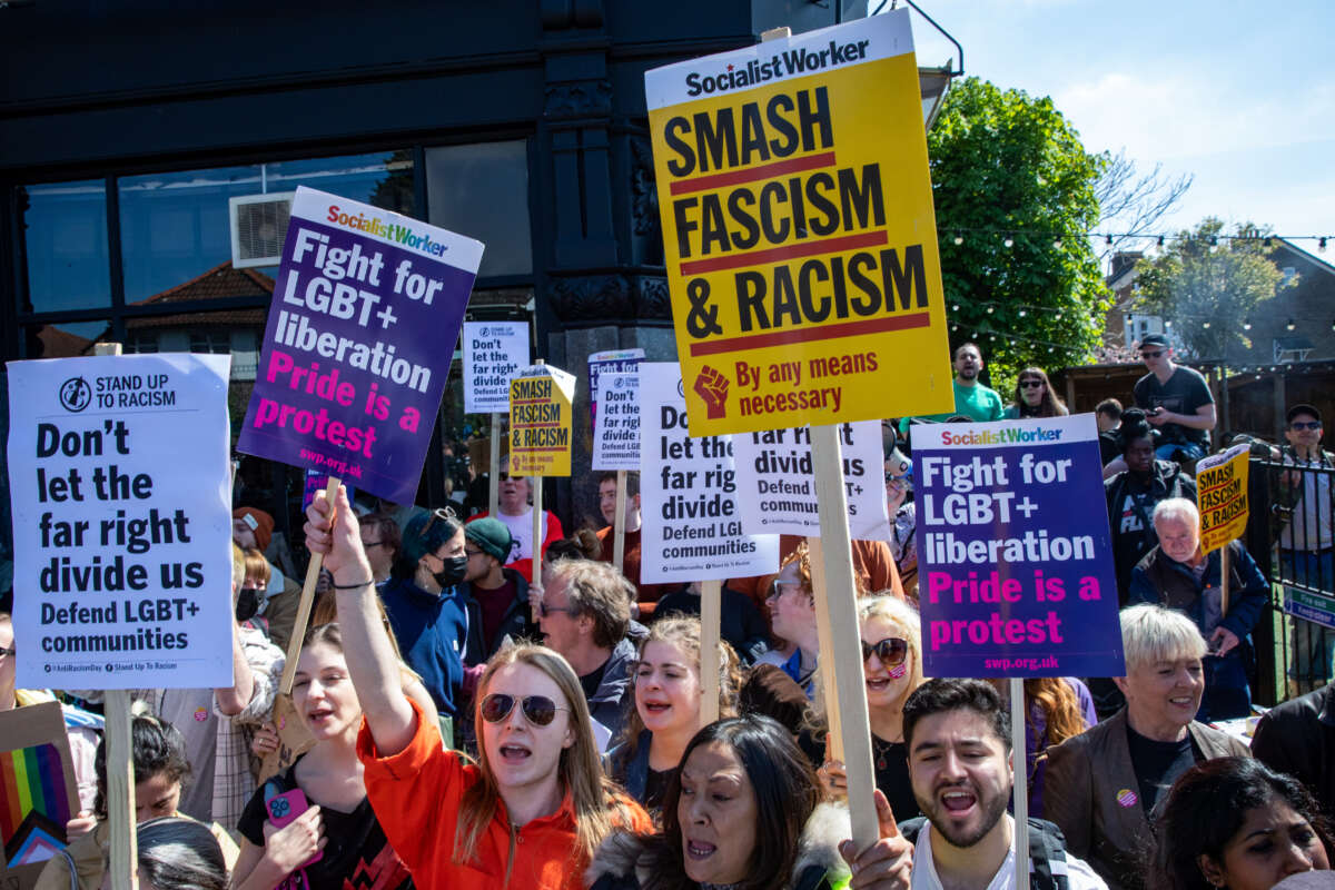 Protestors hold signs saying "Smash Fascism & Racism" and "Don't Let the Far Right Divide Us"