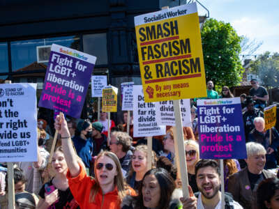 Protestors hold signs saying "Smash Fascism & Racism" and "Don't Let the Far Right Divide Us"