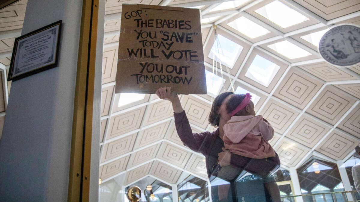 A demonstrator holds a sign and a baby outside a House Floor gallery window at the North Carolina State Legislature after Republican state lawmakers announced their plan to limit abortion rights across the state on May 3, 2023.