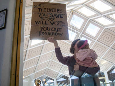 A demonstrator holds a sign and a baby outside a House Floor gallery window at the North Carolina State Legislature after Republican state lawmakers announced their plan to limit abortion rights across the state on May 3, 2023.