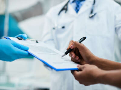 Close-up of African American woman signing paperwork during medical appointment at clinic.