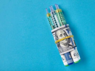 Insulin syringe pens wrapped in dollar bills on a blue background