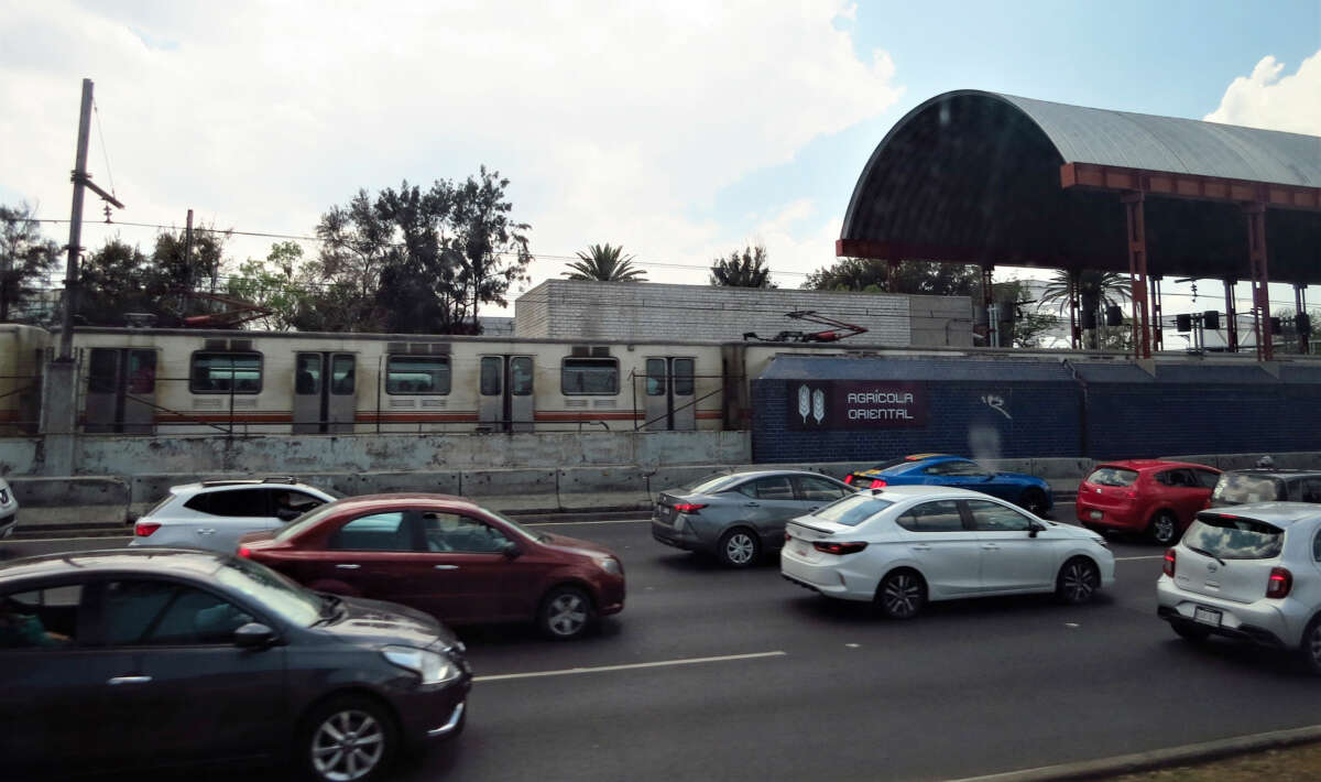 A train in Mexico City, along side a main road.